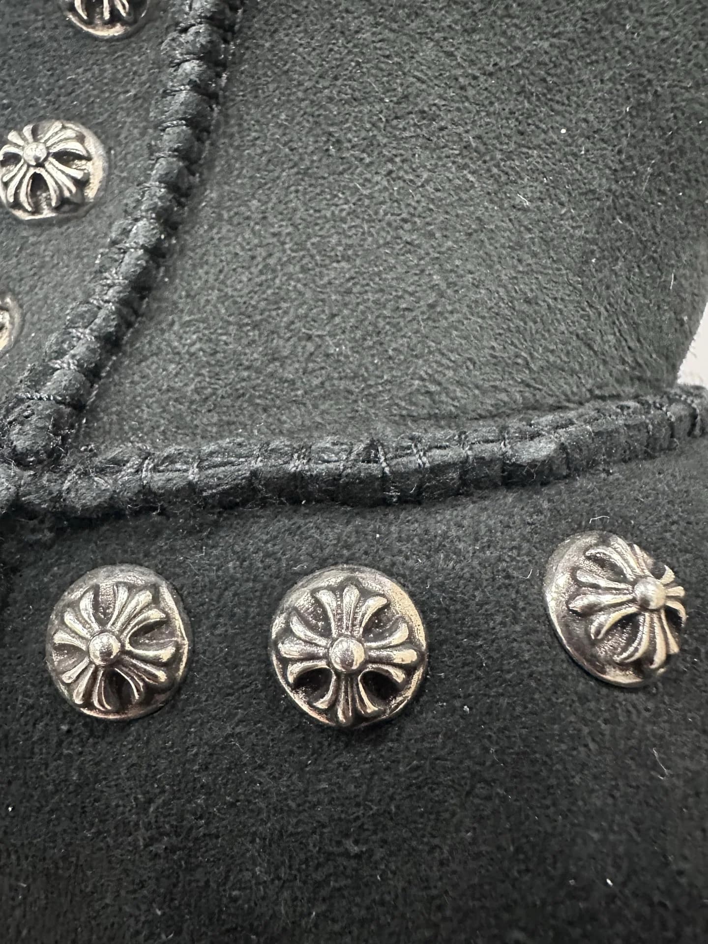 Деталь отделки черных уггов Chrome Hearts с металлическими заклепками-крестами крупным планом