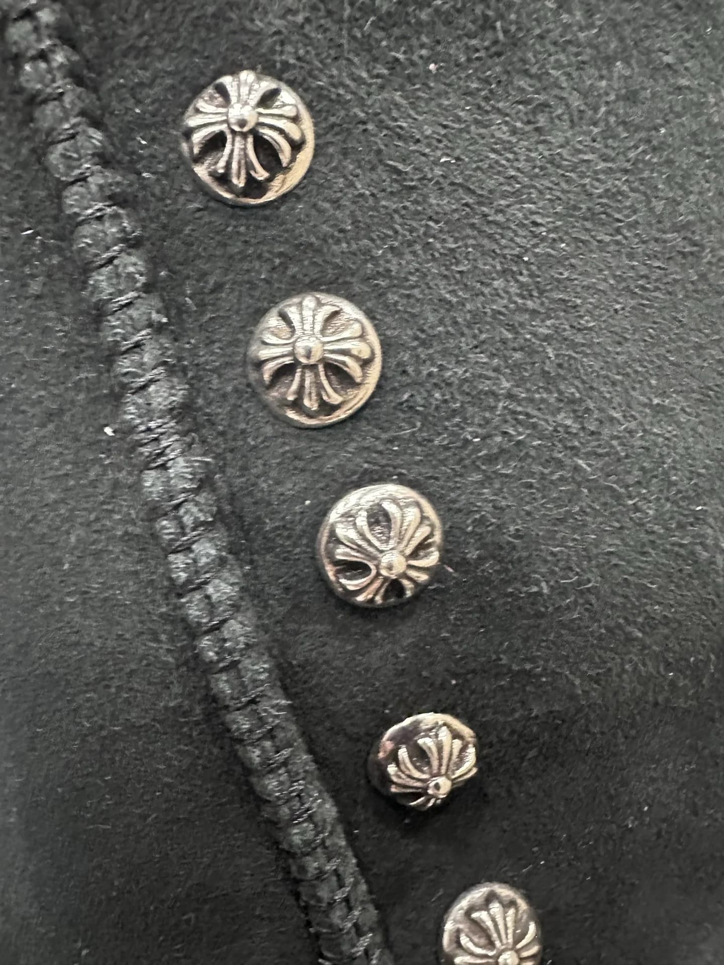 Металлические заклепки в виде крестов Chrome Hearts на черной замше крупным планом