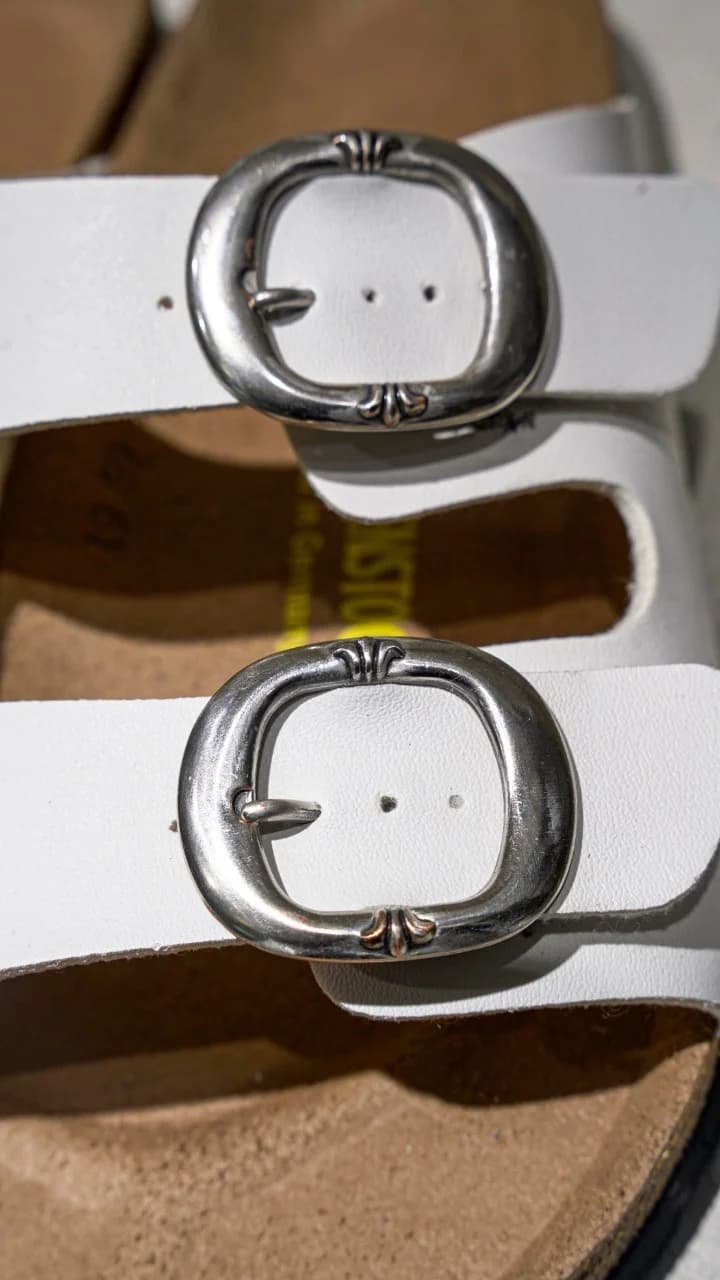 Крупный план серебряной пряжки с гравировкой креста на сандалиях Chrome Hearts x Birkenstock