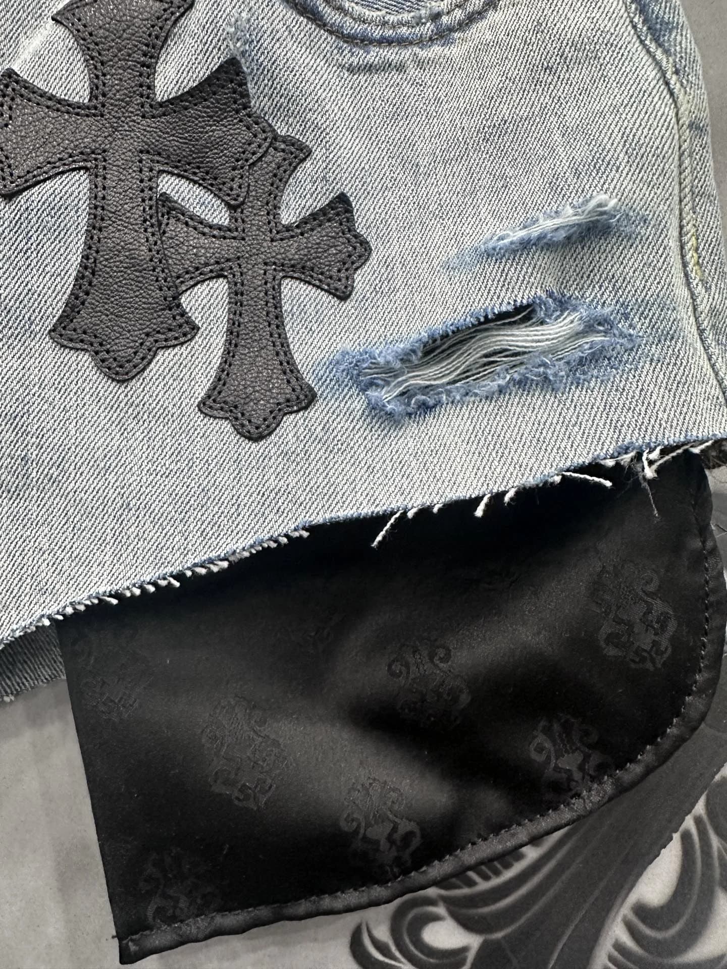 Крупный план: кожаные нашивки-кресты и рваный край джинсовых шорт Chrome Hearts