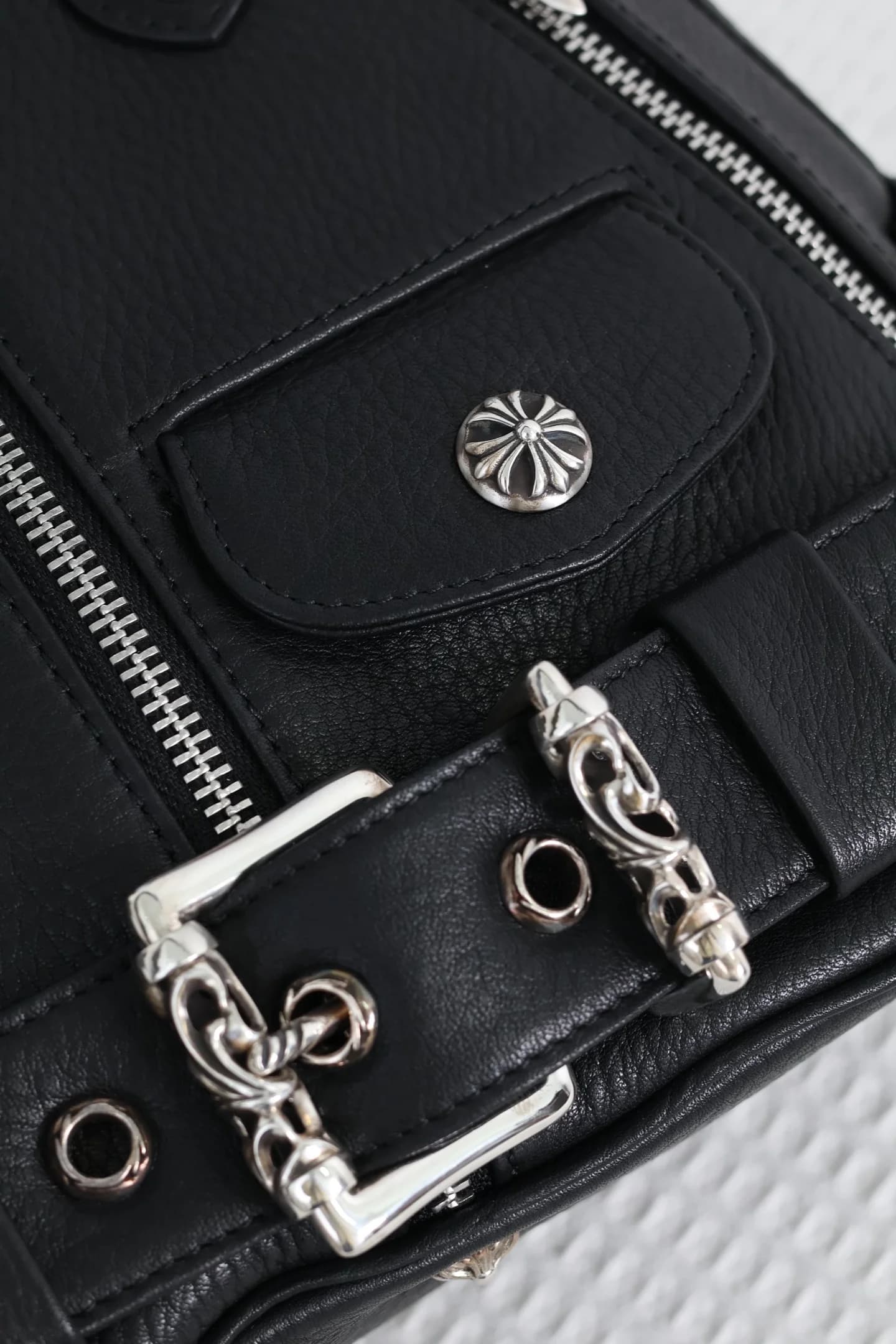 Деталь пряжки и заклепки с крестом на сумке Chrome Hearts