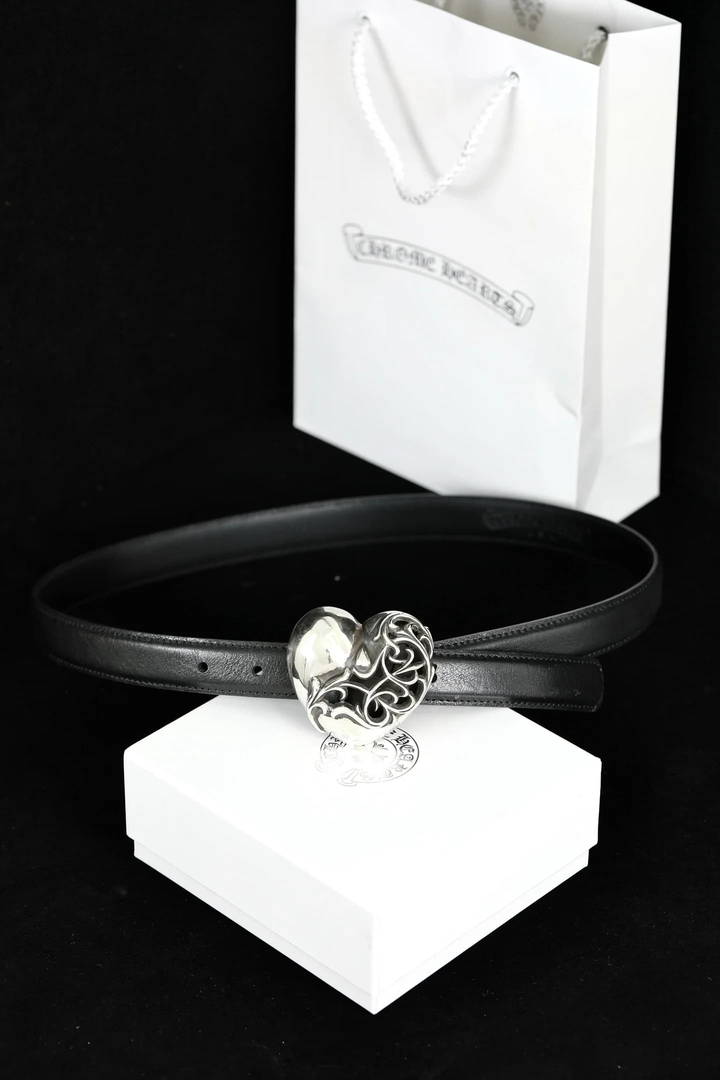 Чёрный кожаный ремень Chrome Hearts с серебряной пряжкой Heart на фоне коробки и пакета
