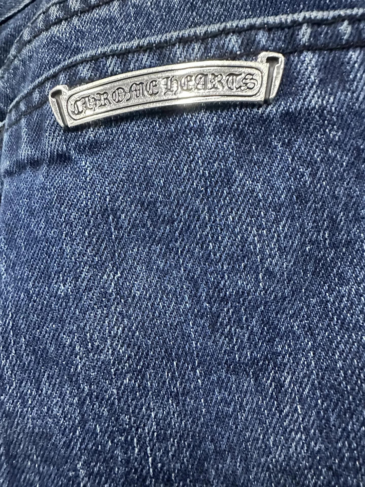 Металлическая пластина с гравировкой Chrome Hearts на заднем кармане джинсов
