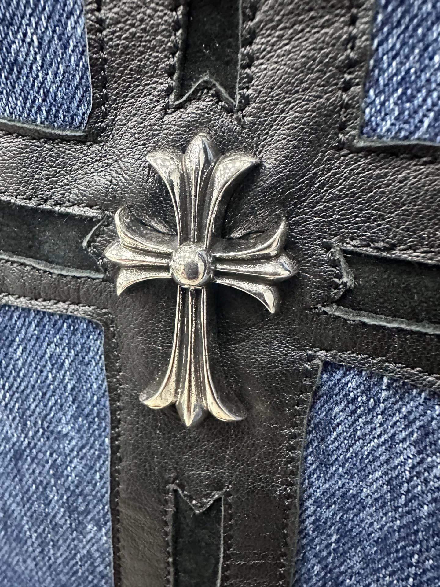 Серебряная деталь в виде креста на кожаном патче джинсов Chrome Hearts