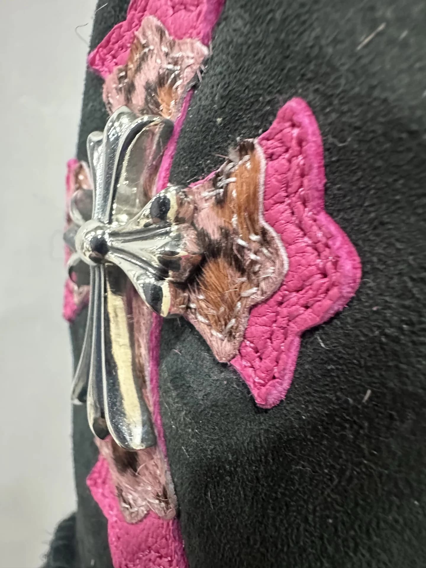 Крупный план серебряной фурнитуры в виде креста Chrome Hearts на сапогах UGG