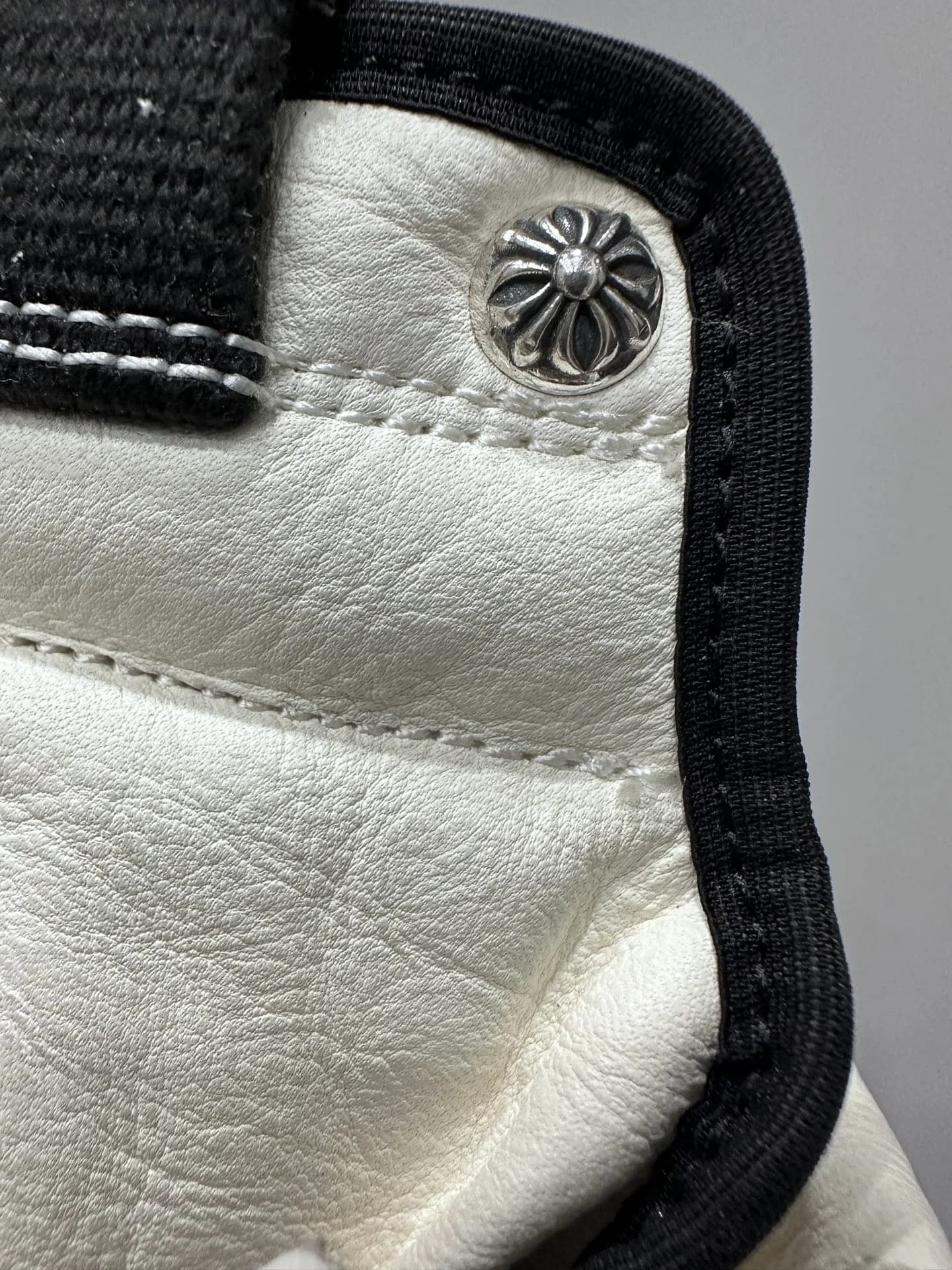 Крупный план кожаной отделки и серебряной кнопки Chrome Hearts