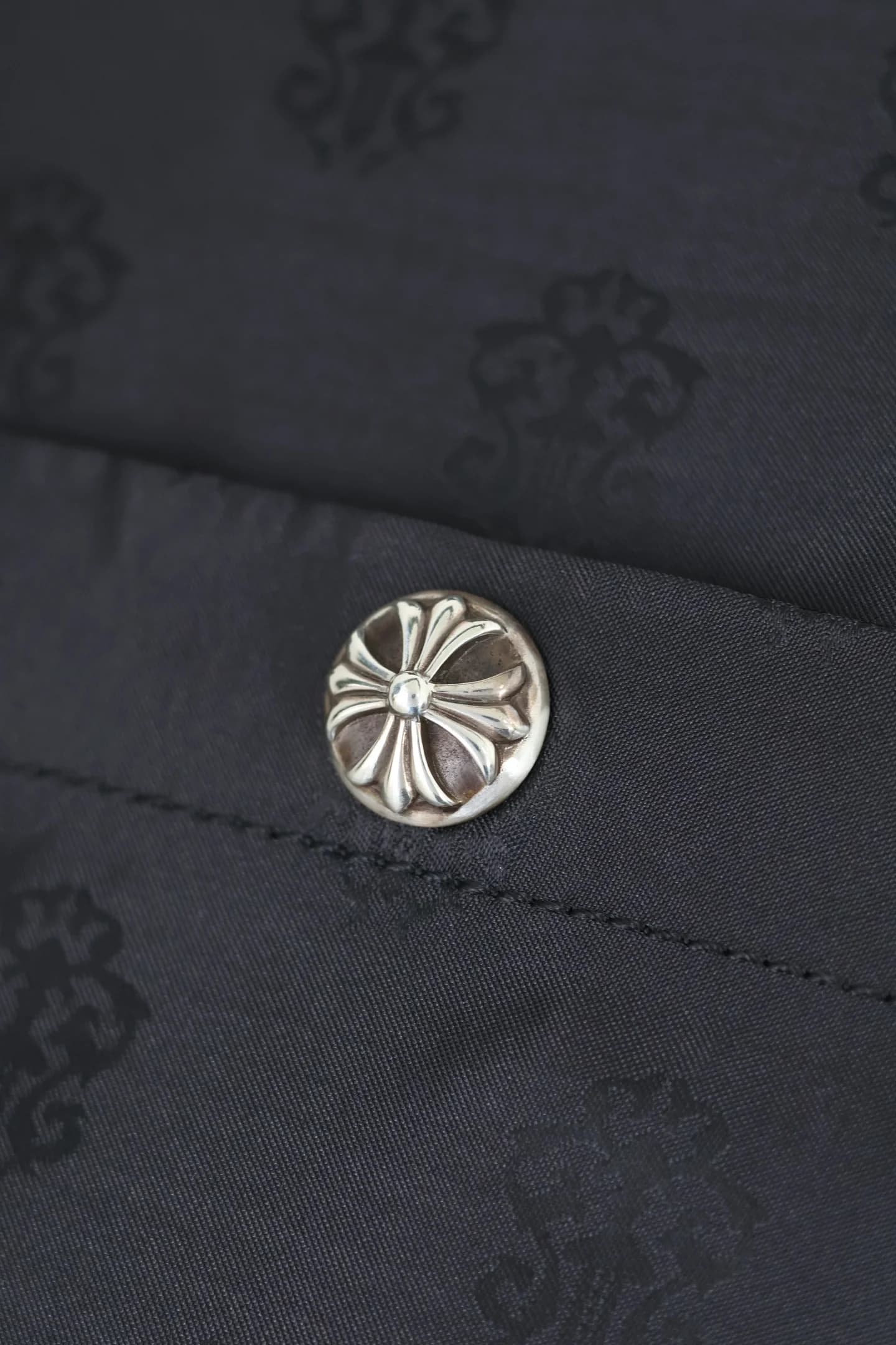 Крупный план серебряной кнопки с гравировкой креста Chrome Hearts