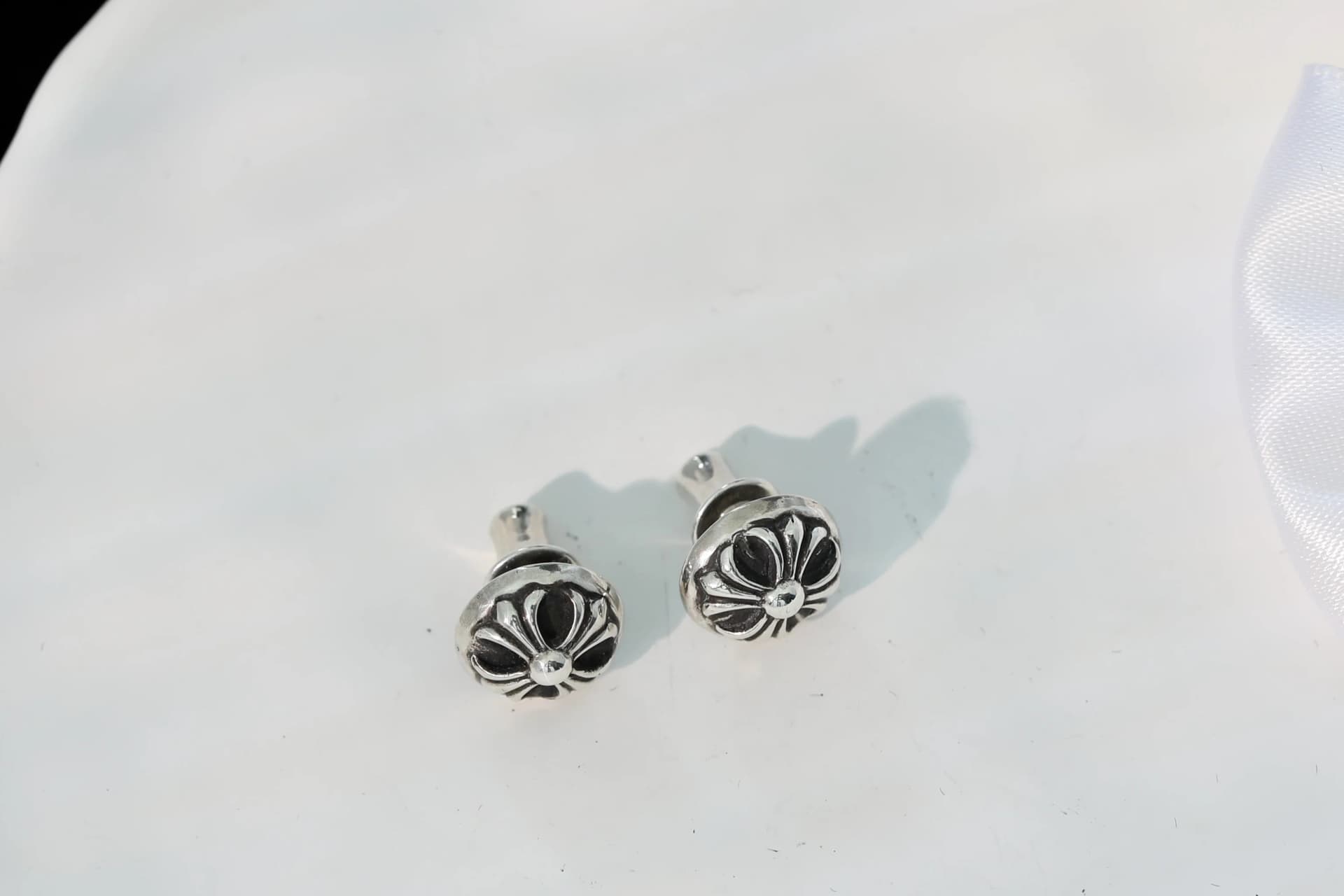 Пара серебряных серег Chrome Hearts ракурсом сверху