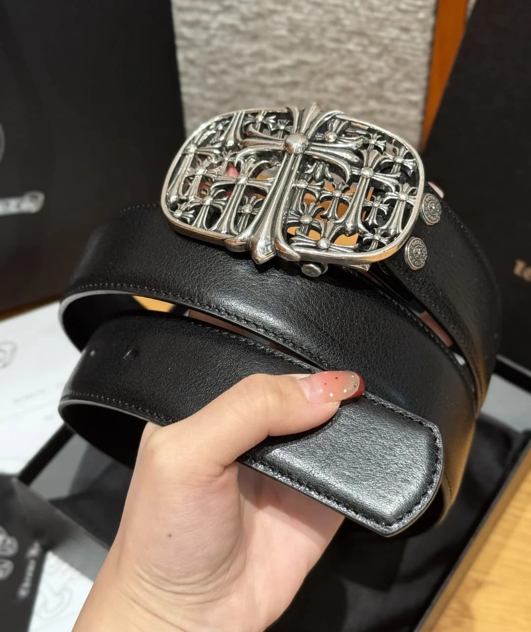 Кожаный ремень Chrome Hearts с массивной фигурной пряжкой в руке