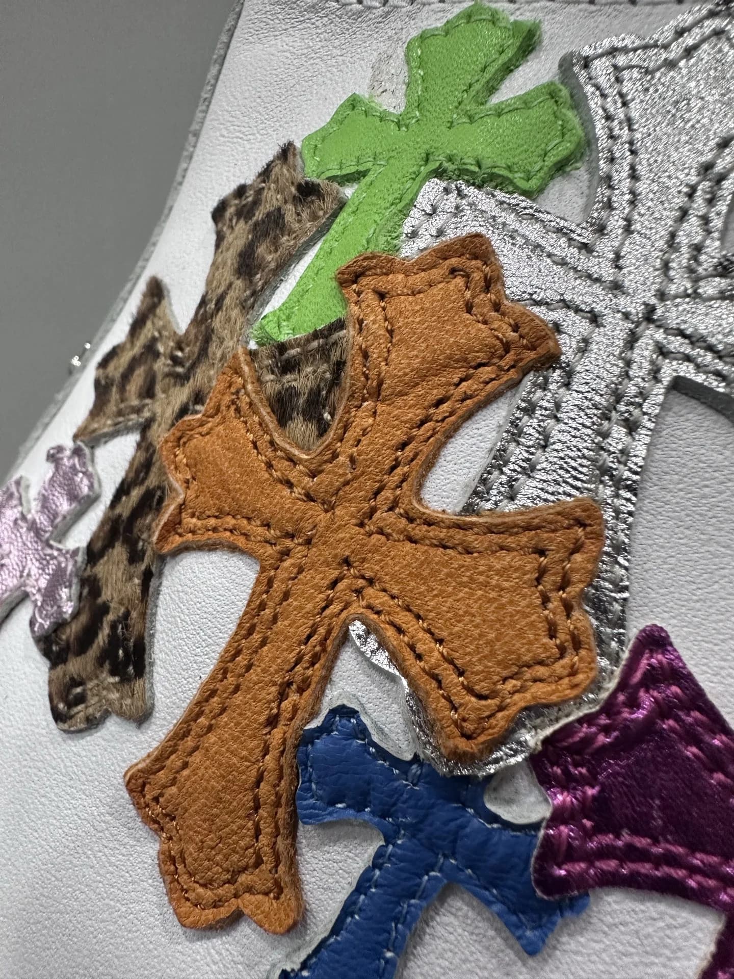 Деталь разноцветных кожаных нашивок в виде крестов на кедах Chrome Hearts