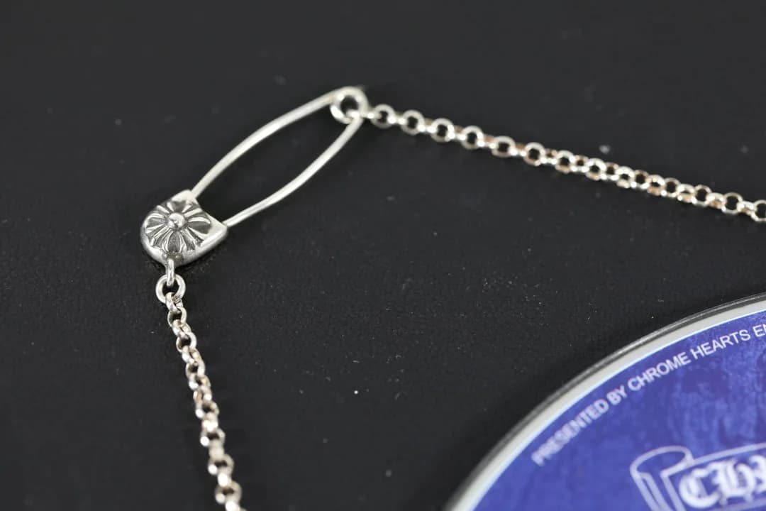 Крупный план декоративного элемента булавки серебряного колье Chrome Hearts