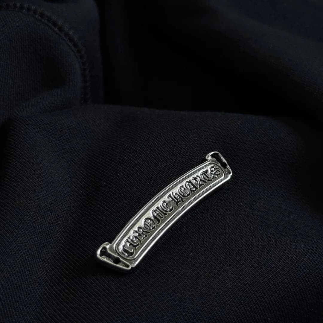 Деталь металлической плашки Chrome Hearts на черном трикотаже
