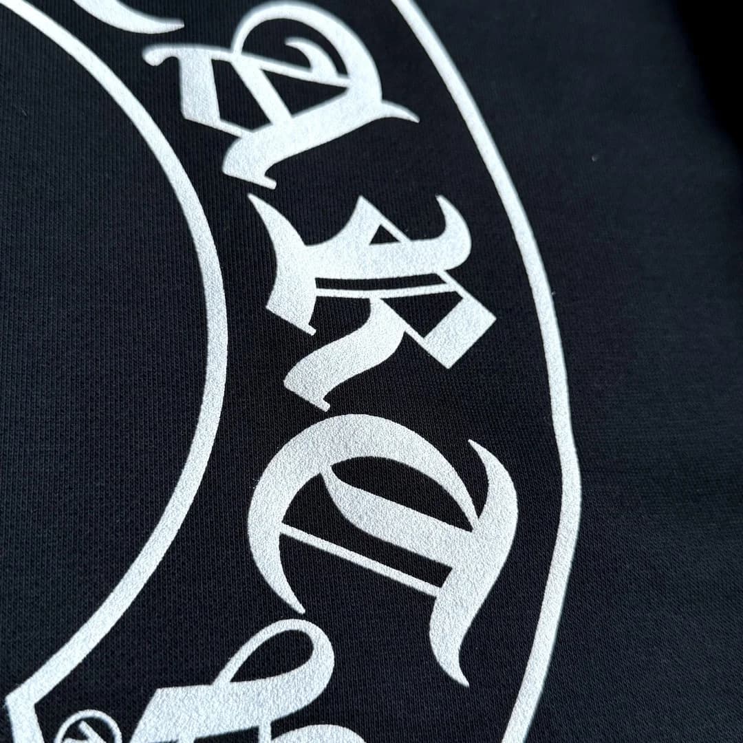 Деталь белого принта Chrome Hearts на черной ткани