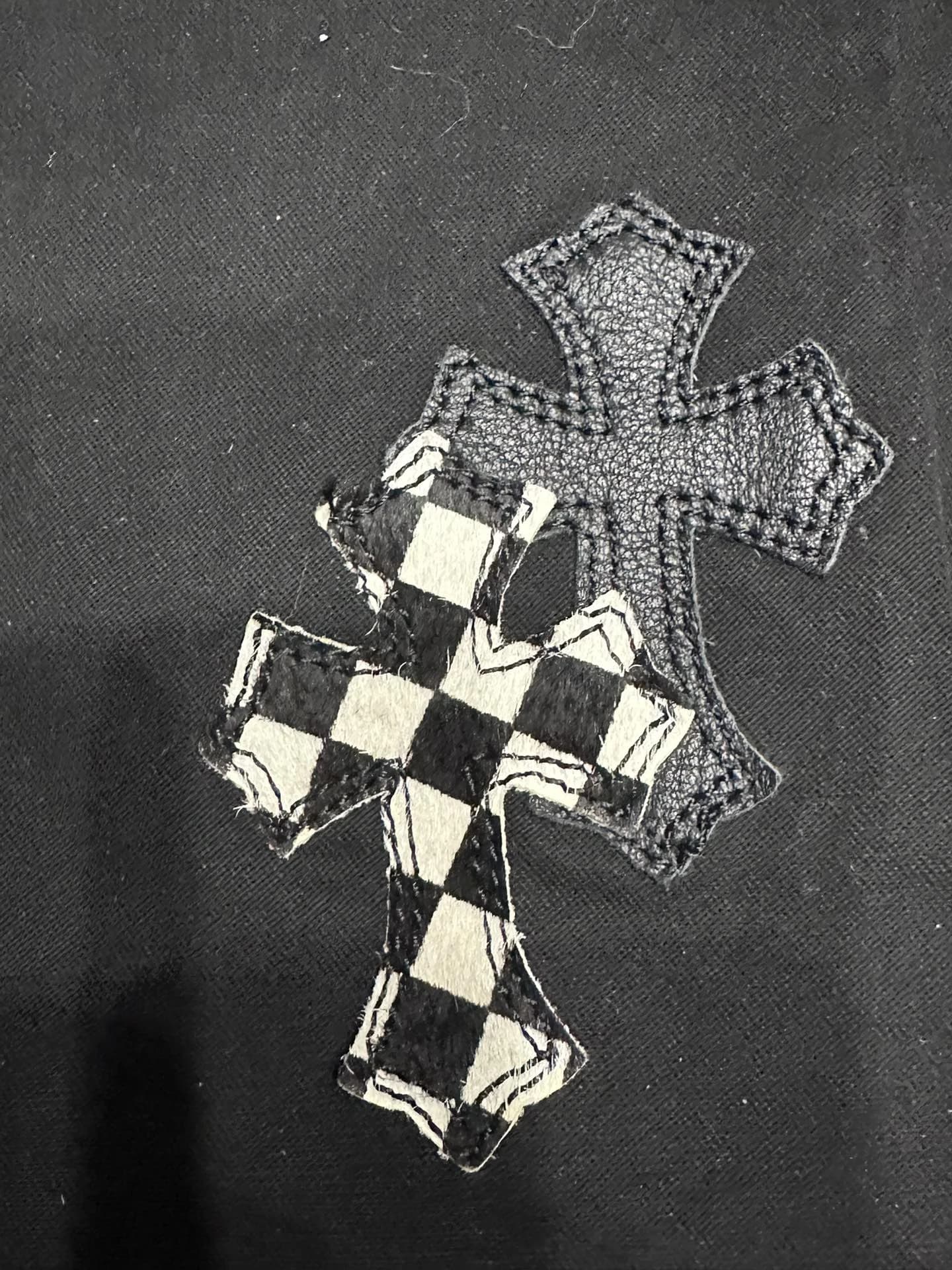 Крупный план кожаных нашивок-крестов на черных джинсах Chrome Hearts