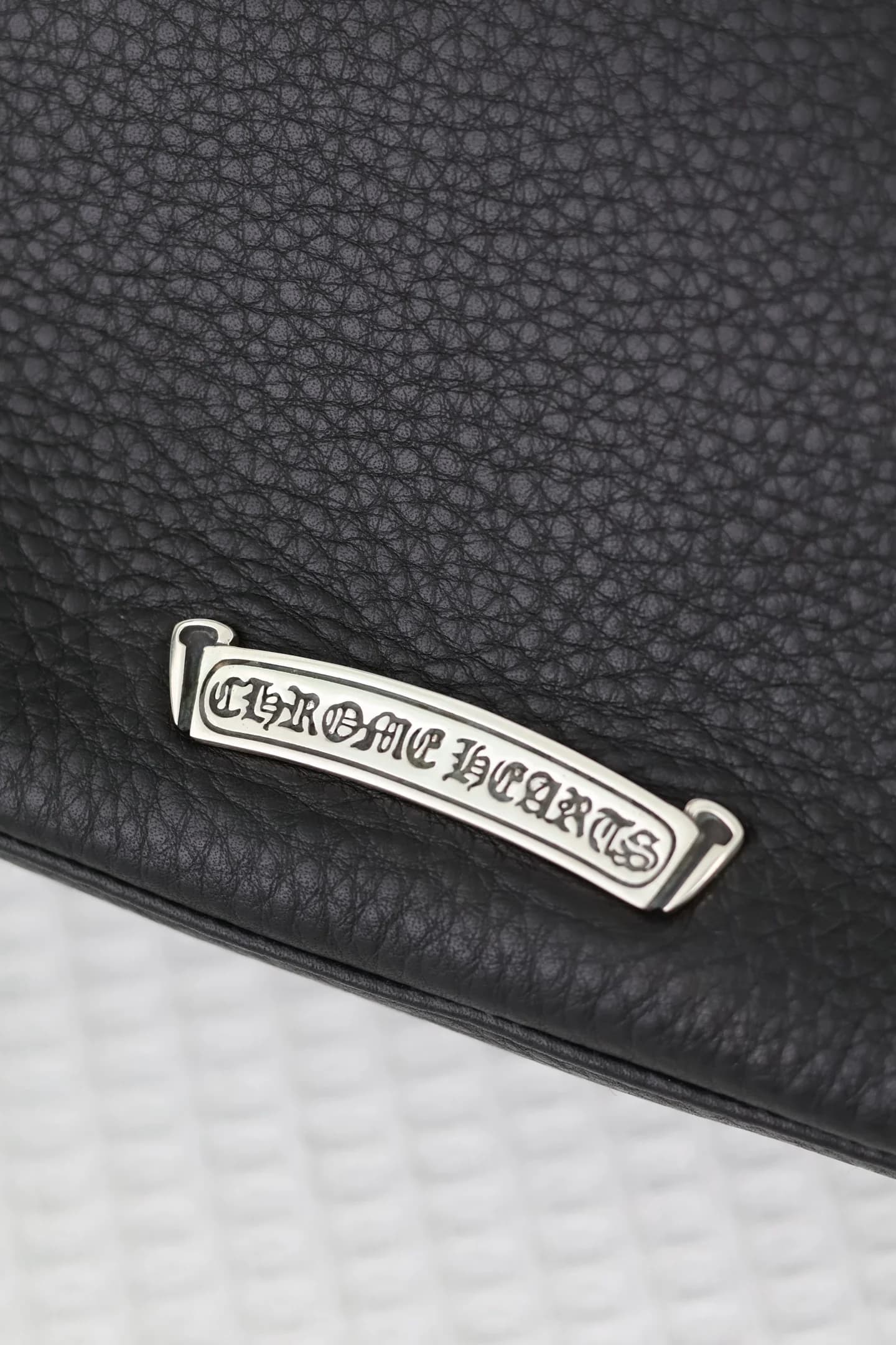 Серебряная плашка с логотипом Chrome Hearts на задней панели сумки