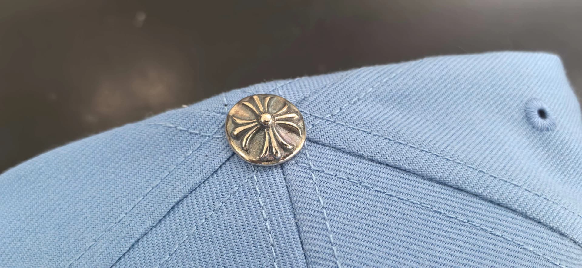 Деталь серебряной кнопки в виде креста на бейсболке Chrome Hearts