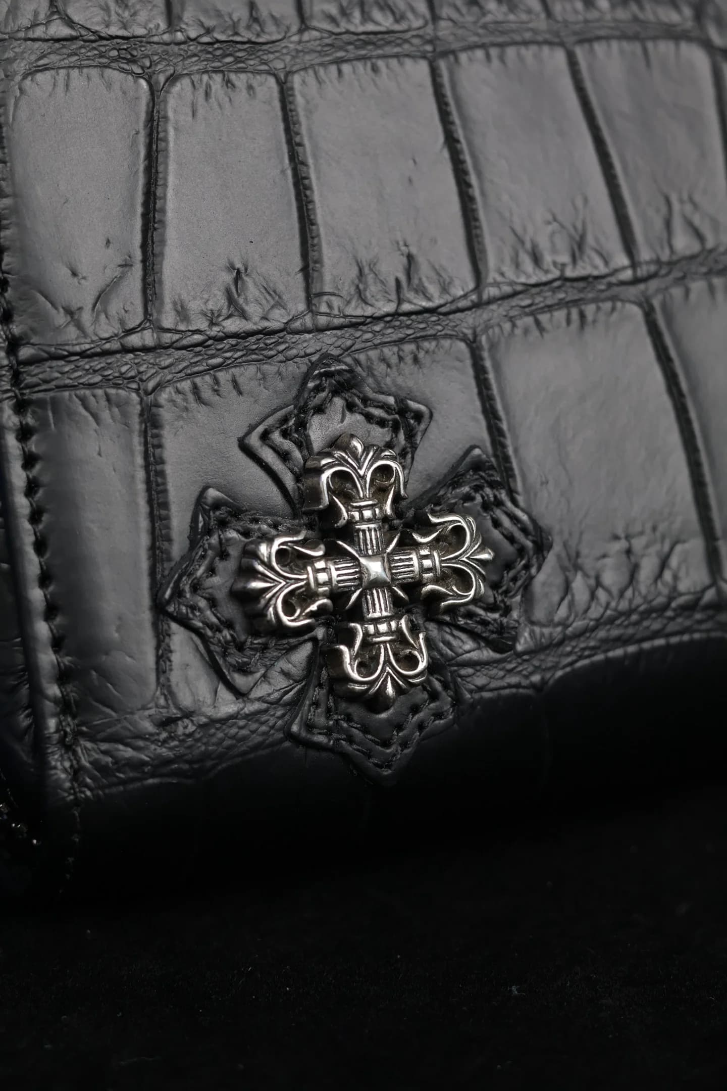 Деталь серебряного креста Chrome Hearts на фактурной коже крокодила