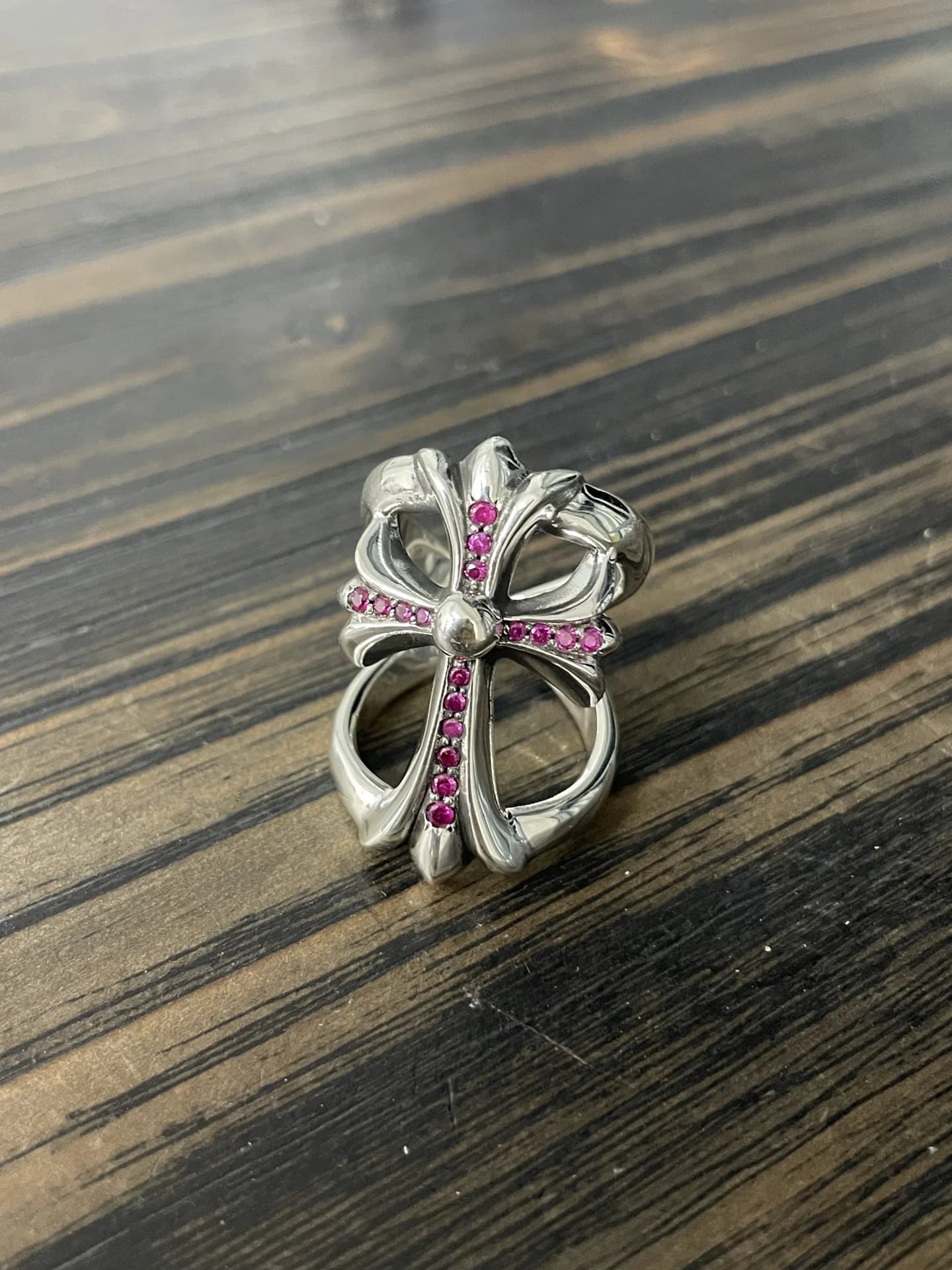 Серебряное кольцо Chrome Hearts Infinity с красными бриллиантами на деревянной поверхности