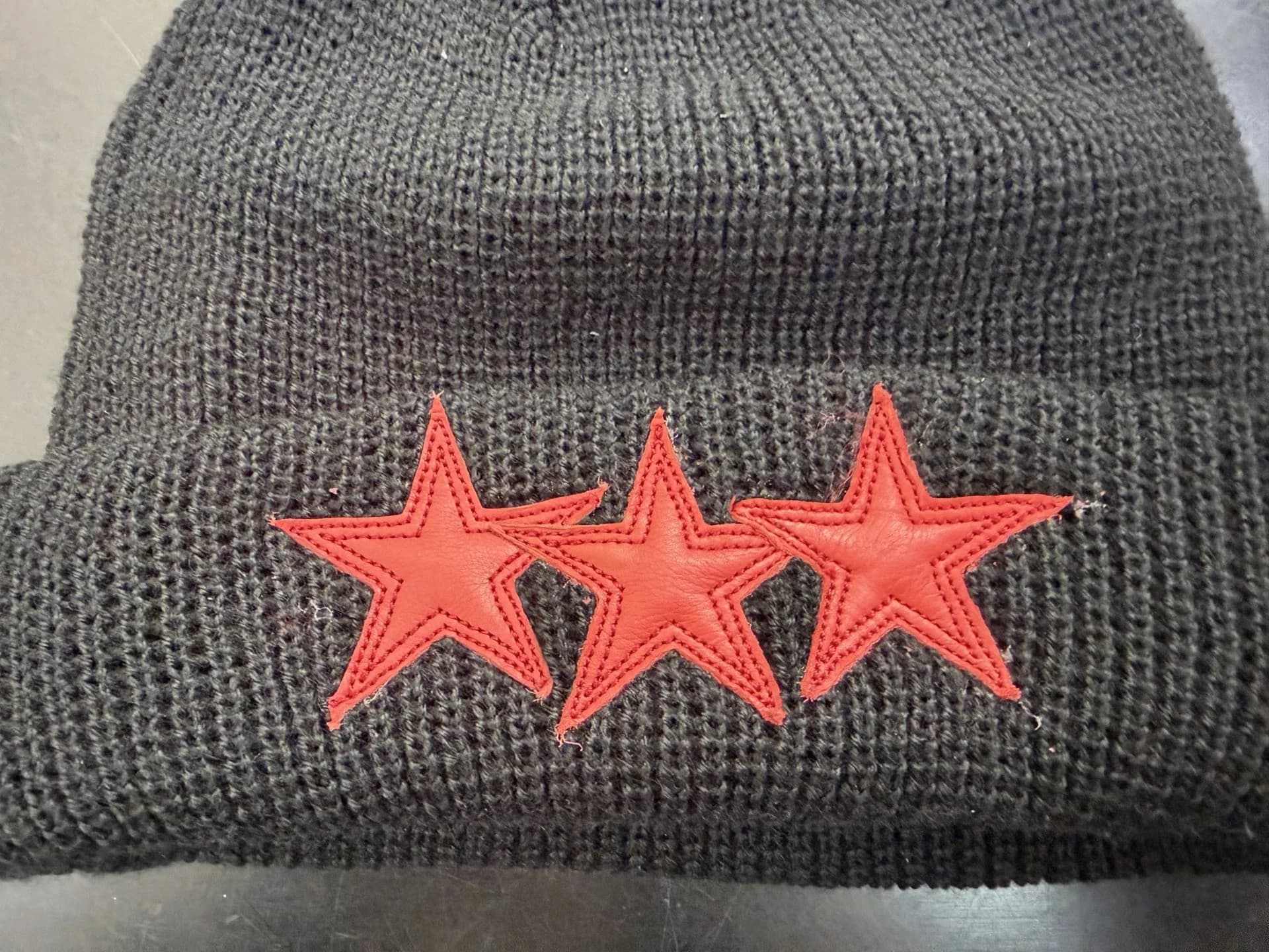 Деталь отворота шапки Chrome Hearts с красными кожаными звездами
