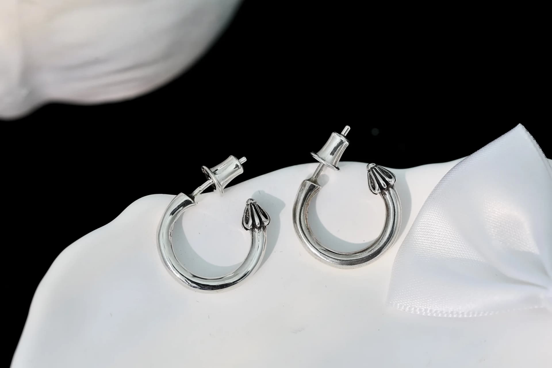 Серебряные серьги-полукольца Chrome Hearts с застежками-пусетами на белом декоративном блюдце