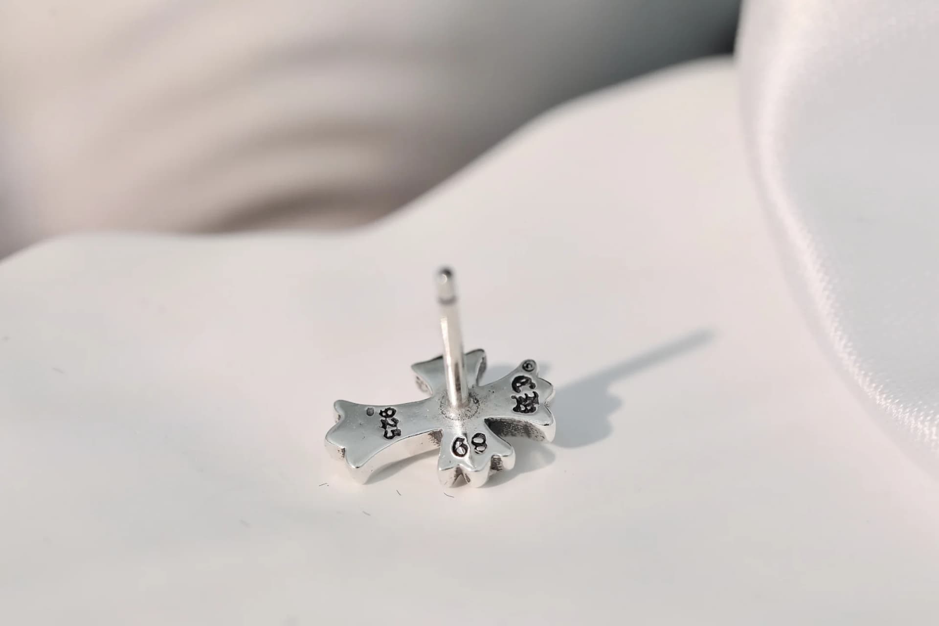 Обратная сторона серьги-пусета с фирменной гравировкой Chrome Hearts и пробой