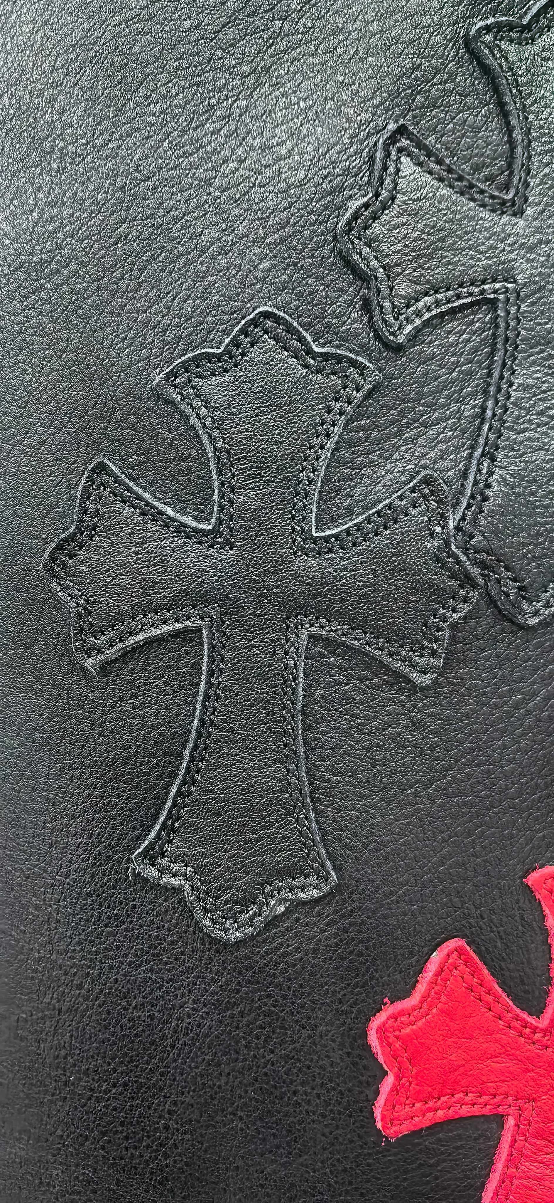 Крупный план кожаной нашивки в виде креста на брюках Chrome Hearts