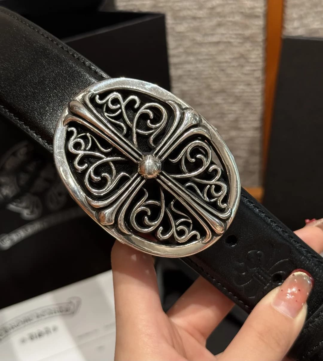 Крупный план овальной серебряной пряжки Chrome Hearts с готическим крестом