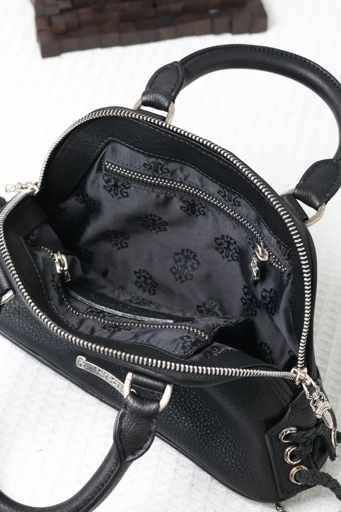 Вид сверху на открытое основное отделение черной сумки Chrome Hearts
