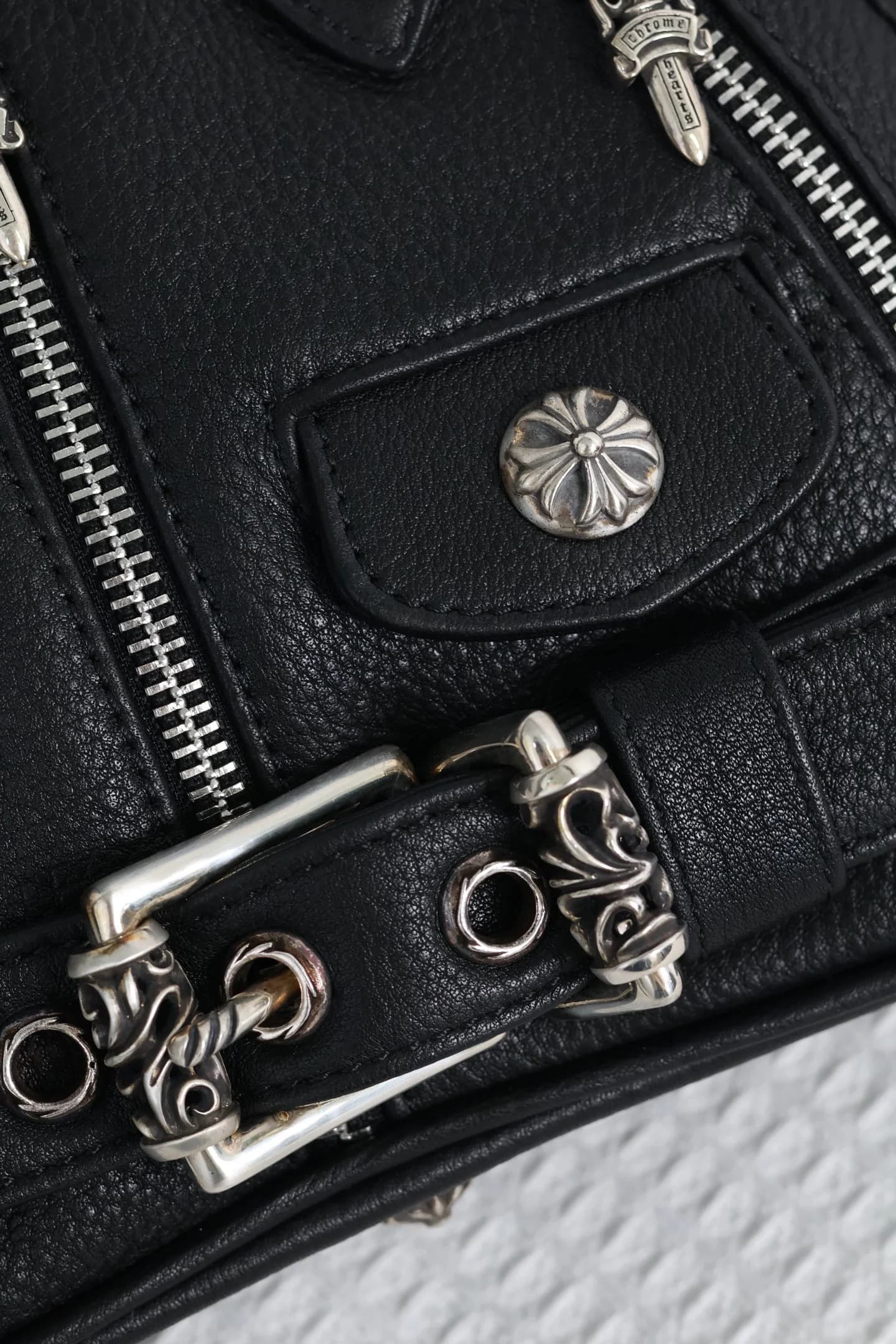Деталь серебряной пряжки и заклепки в виде креста на сумке Chrome Hearts