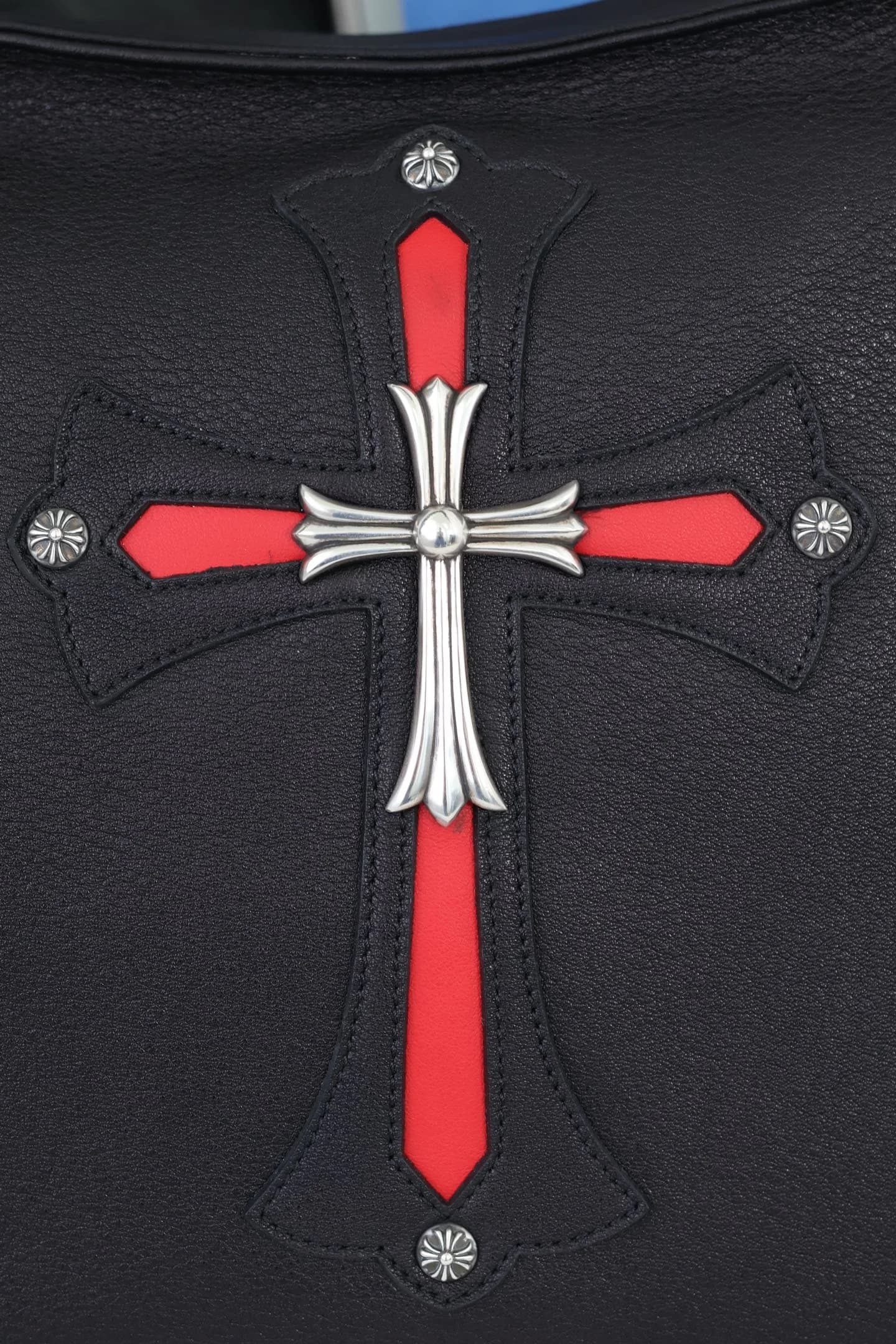 Крупный план кожаной нашивки с крестом и серебряным элементом Chrome Hearts