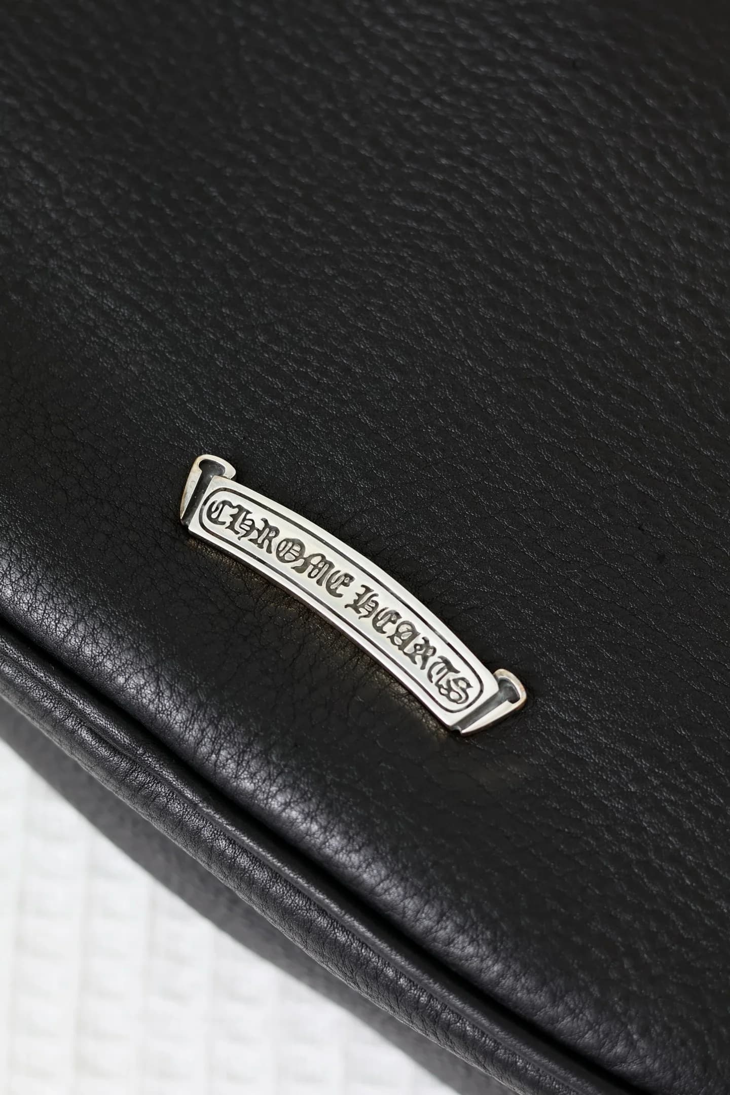 Серебряная плакетка с гравировкой Chrome Hearts на задней панели сумки