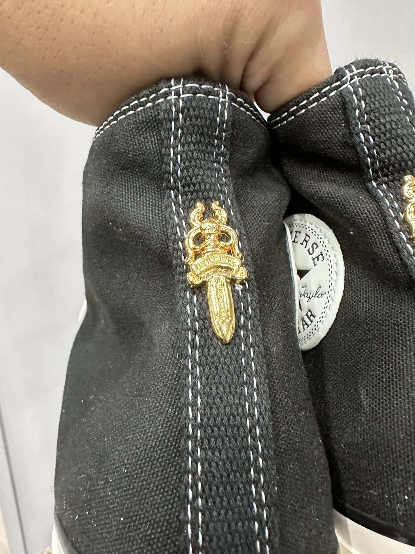 Крупный план золотистого кинжала на заднике кед Chrome Hearts x Converse