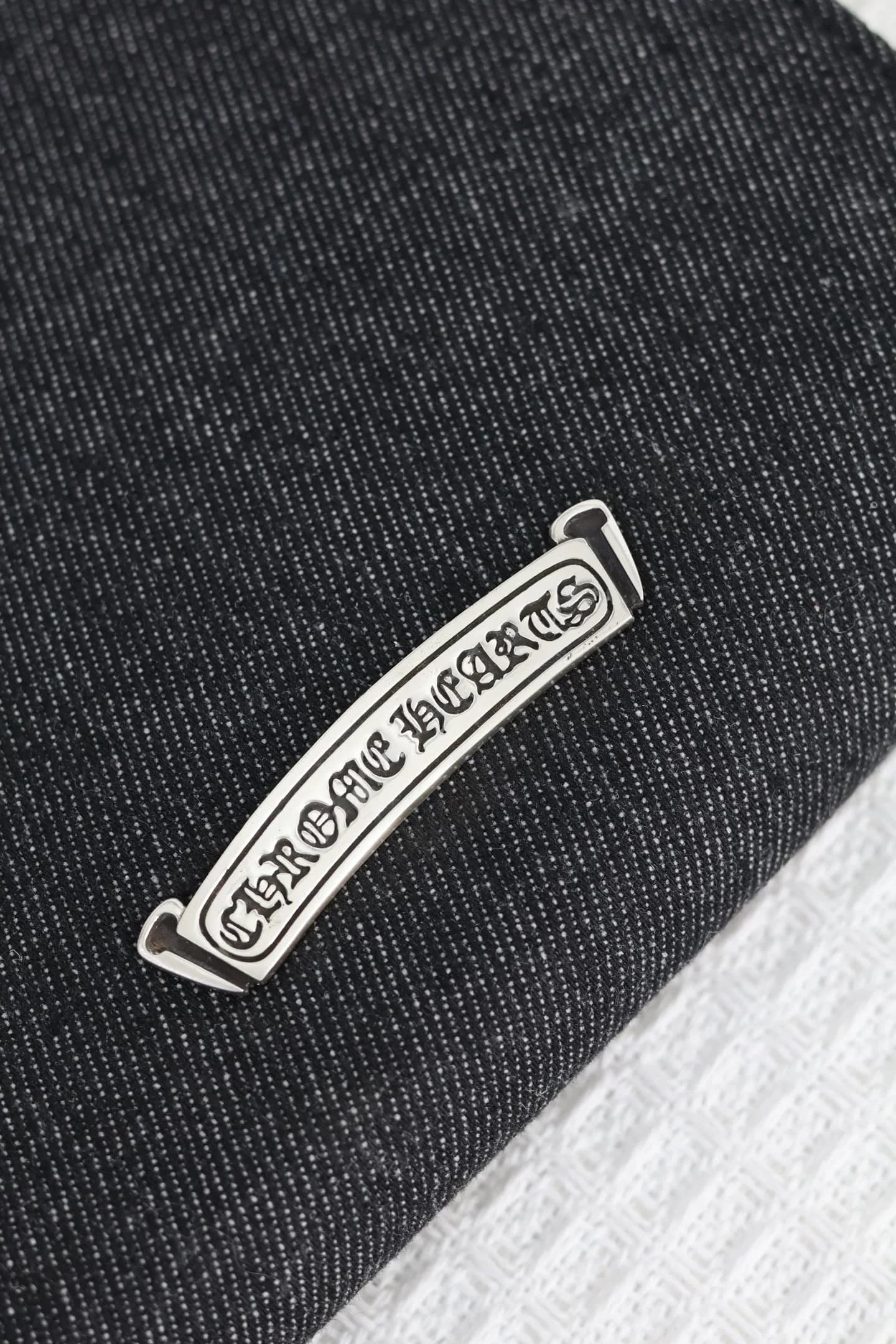 Серебряная плашка с гравировкой Chrome Hearts на задней панели сумки
