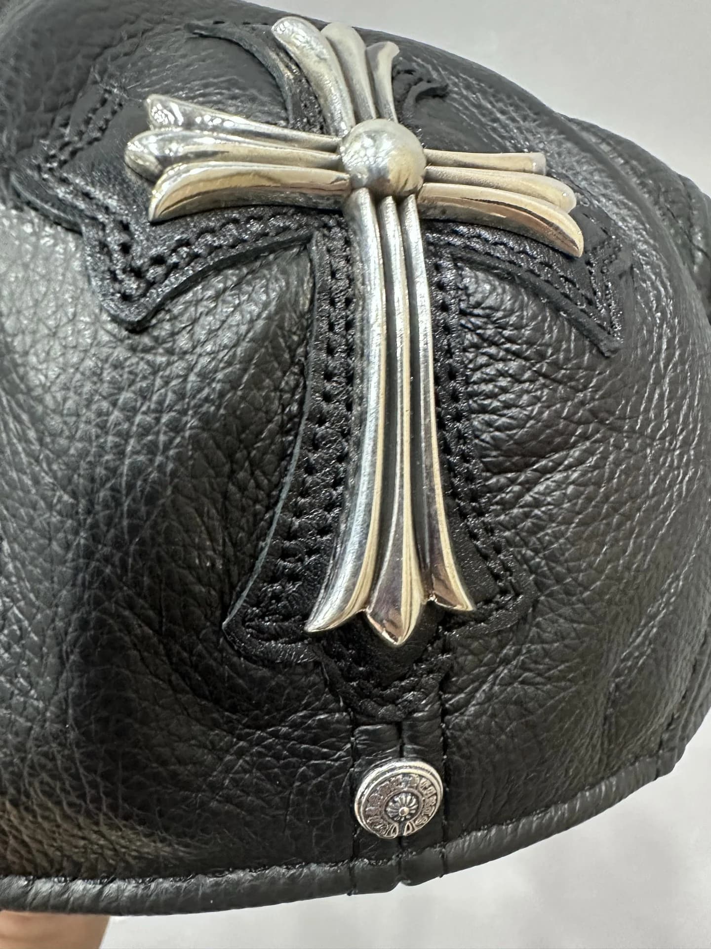 Деталь серебряного креста 925 пробы на кожаной кепке Chrome Hearts