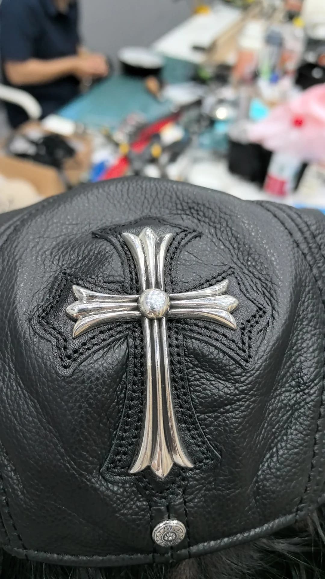 Крупный план серебряного креста на кожаной кепке Chrome Hearts