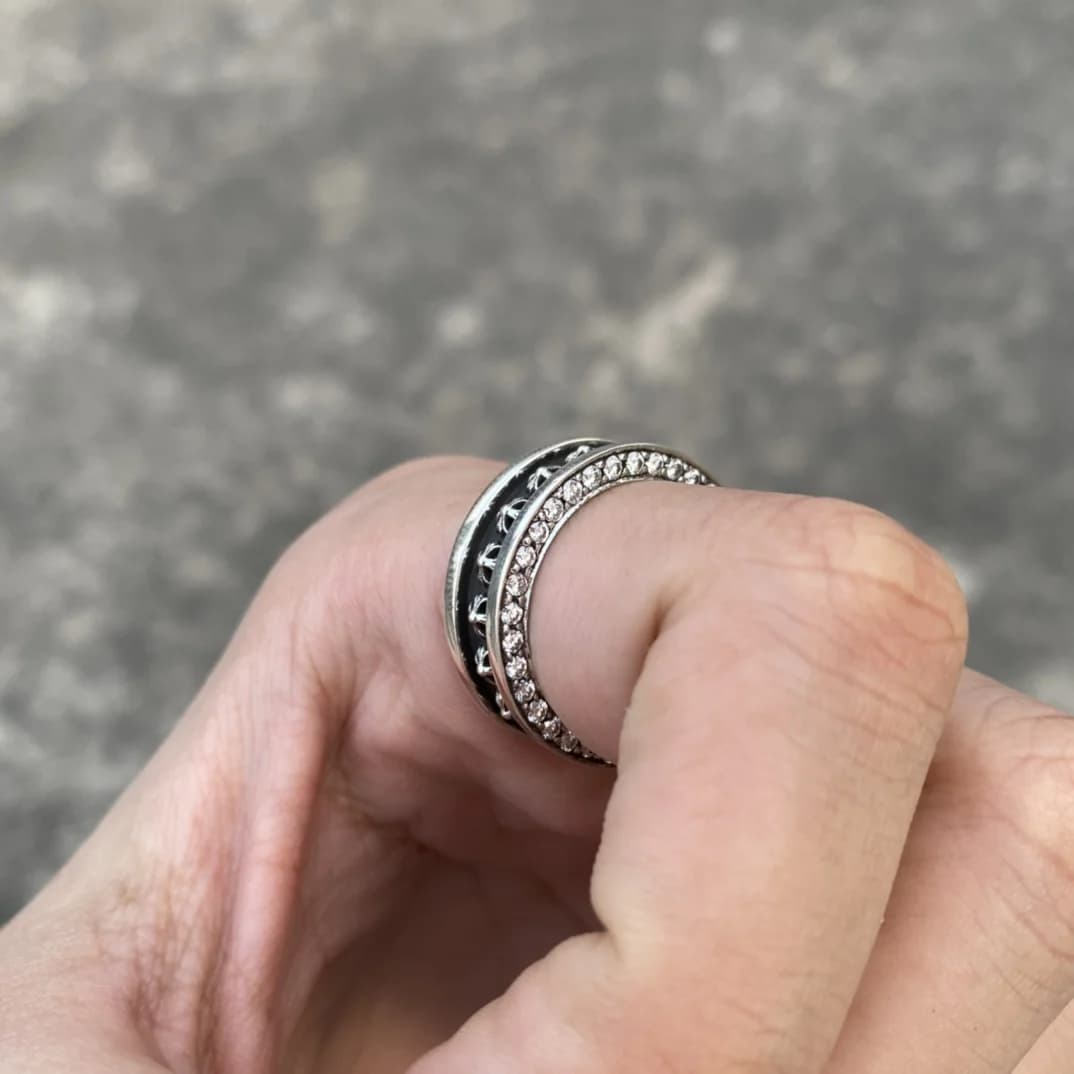 Крупный план кольца Chrome Hearts с инкрустацией камнями на согнутом пальце