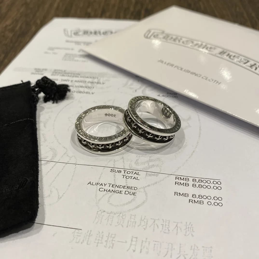 Два кольца Chrome Hearts Plus Cross Band на фоне чека и замшевого мешочка