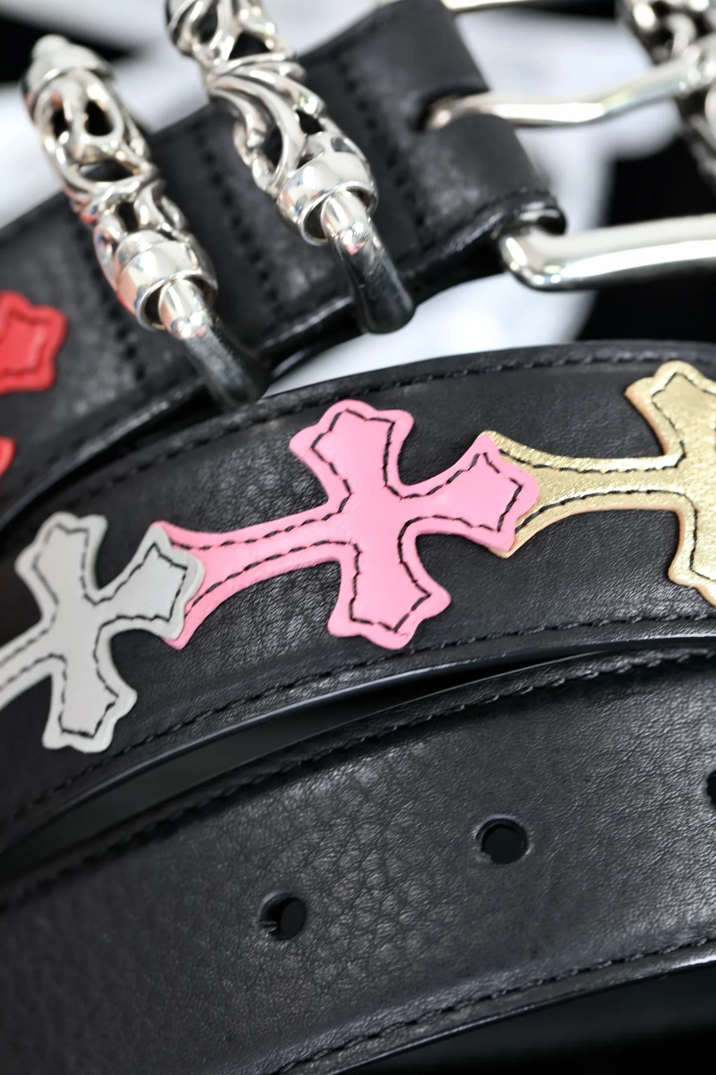 Разноцветные кожаные кресты-нашивки на чёрном полотне ремня Chrome Hearts