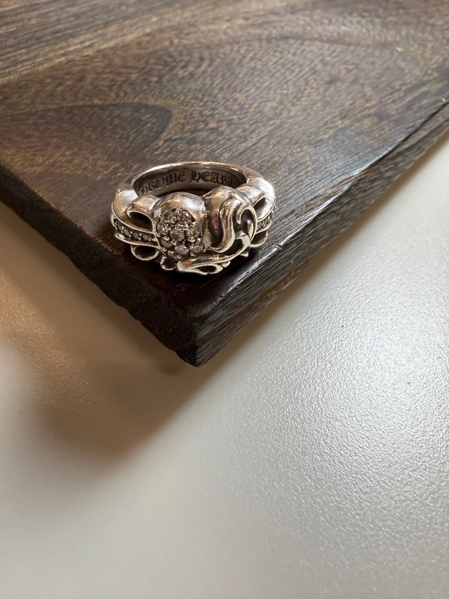 Серебряное кольцо Chrome Hearts Heart с бриллиантами на деревянной поверхности