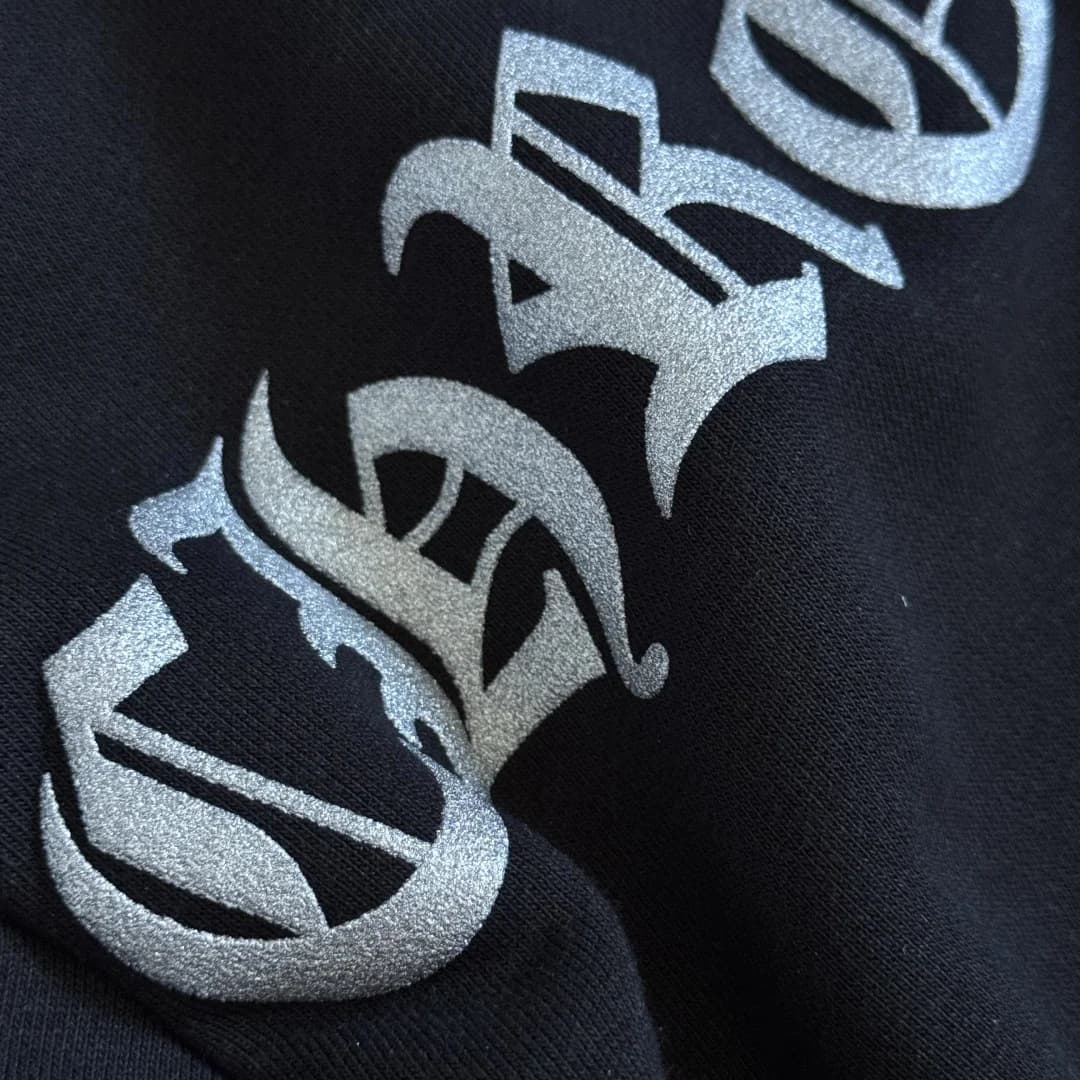 Деталь серебристого принта с готическим шрифтом Chrome Hearts