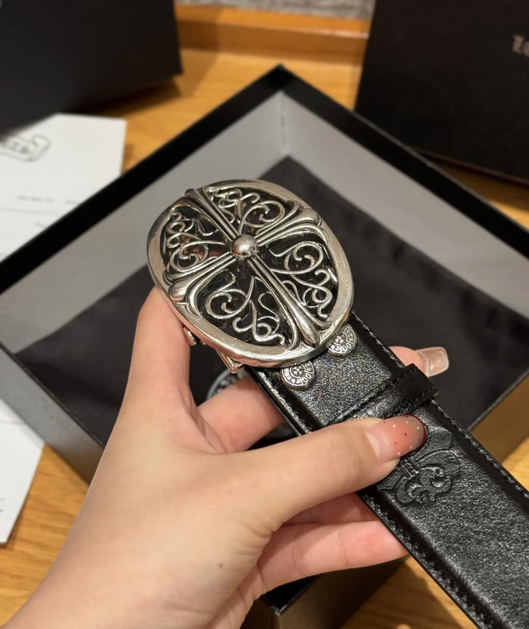 Крупный план фигурной металлической пряжки с крестом Chrome Hearts