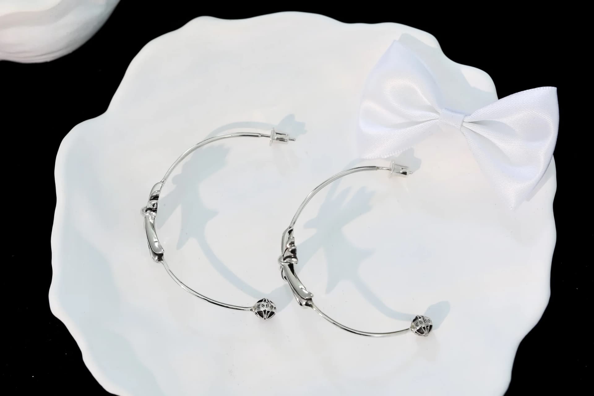Серьги Chrome Hearts изогнутой формы на белом блюдце