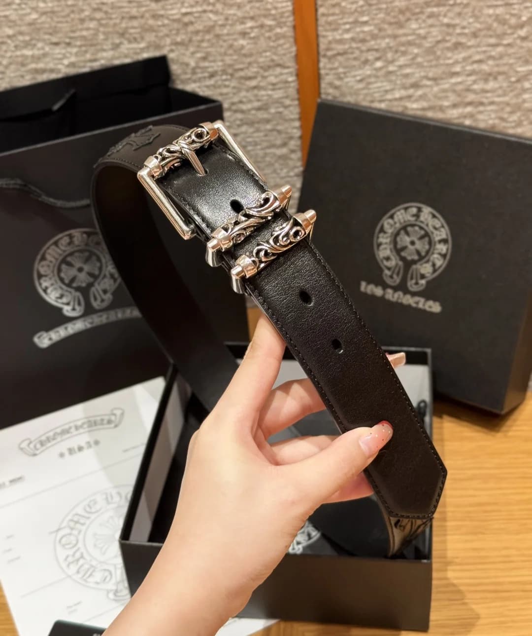 Черный ремень Chrome Hearts с серебряной пряжкой в руке