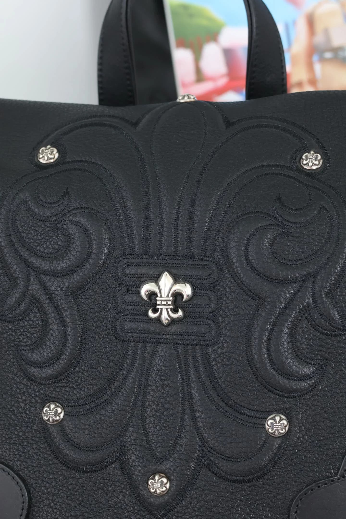 Деталь тиснения на коже с серебряной лилией Fleur-de-lis и заклепками