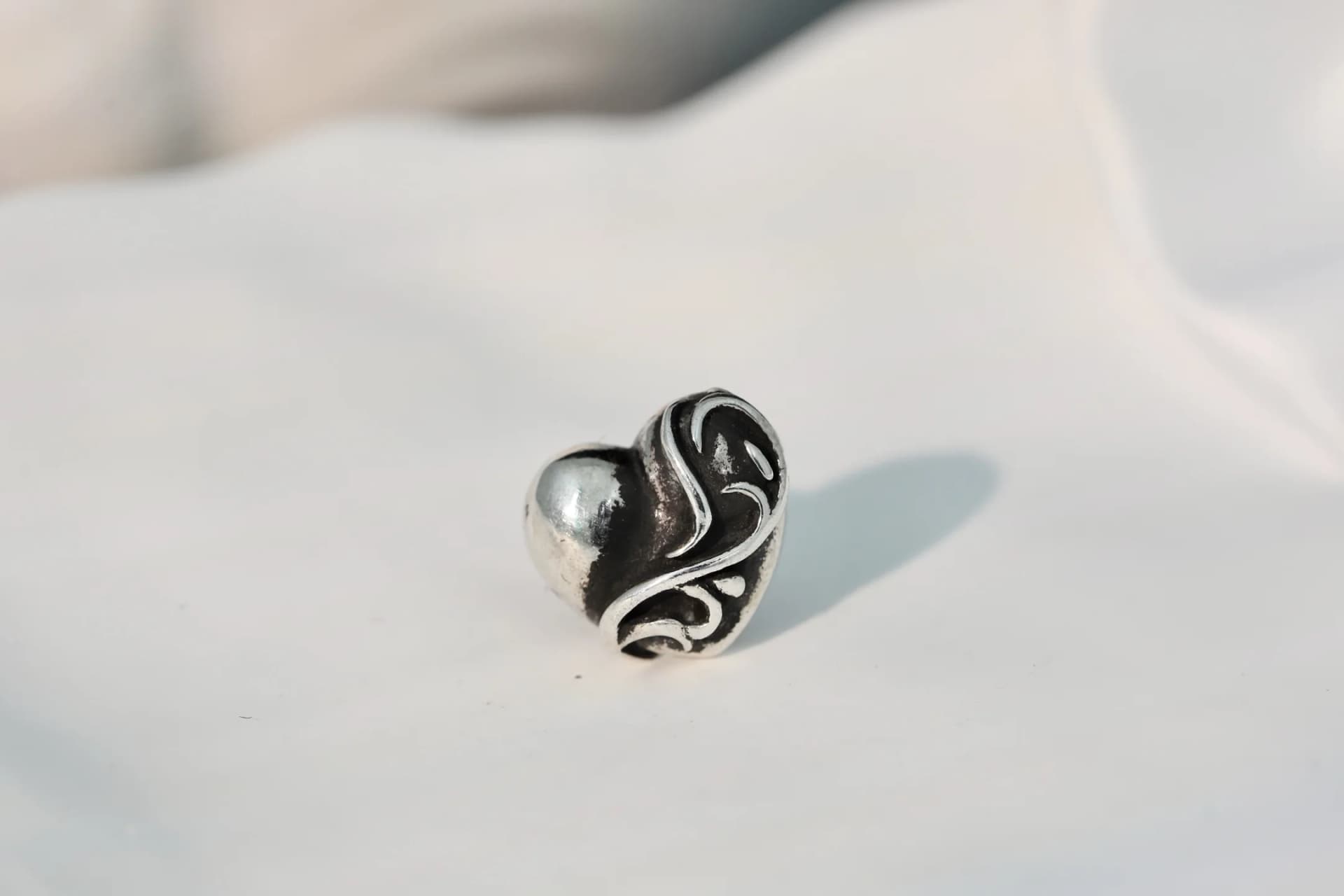 Крупный план резного узора серебряной серьги Chrome Hearts Heart