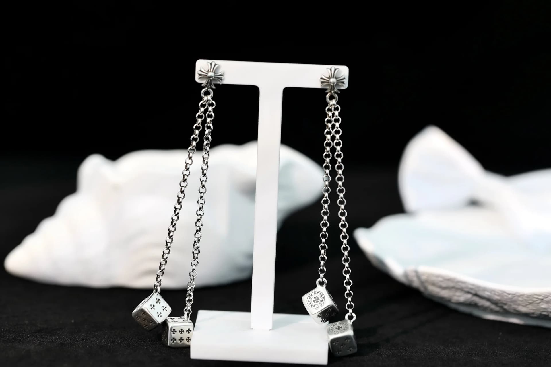 Пара серебряных серег Chrome Hearts с цепочками и игральными костями на подставке