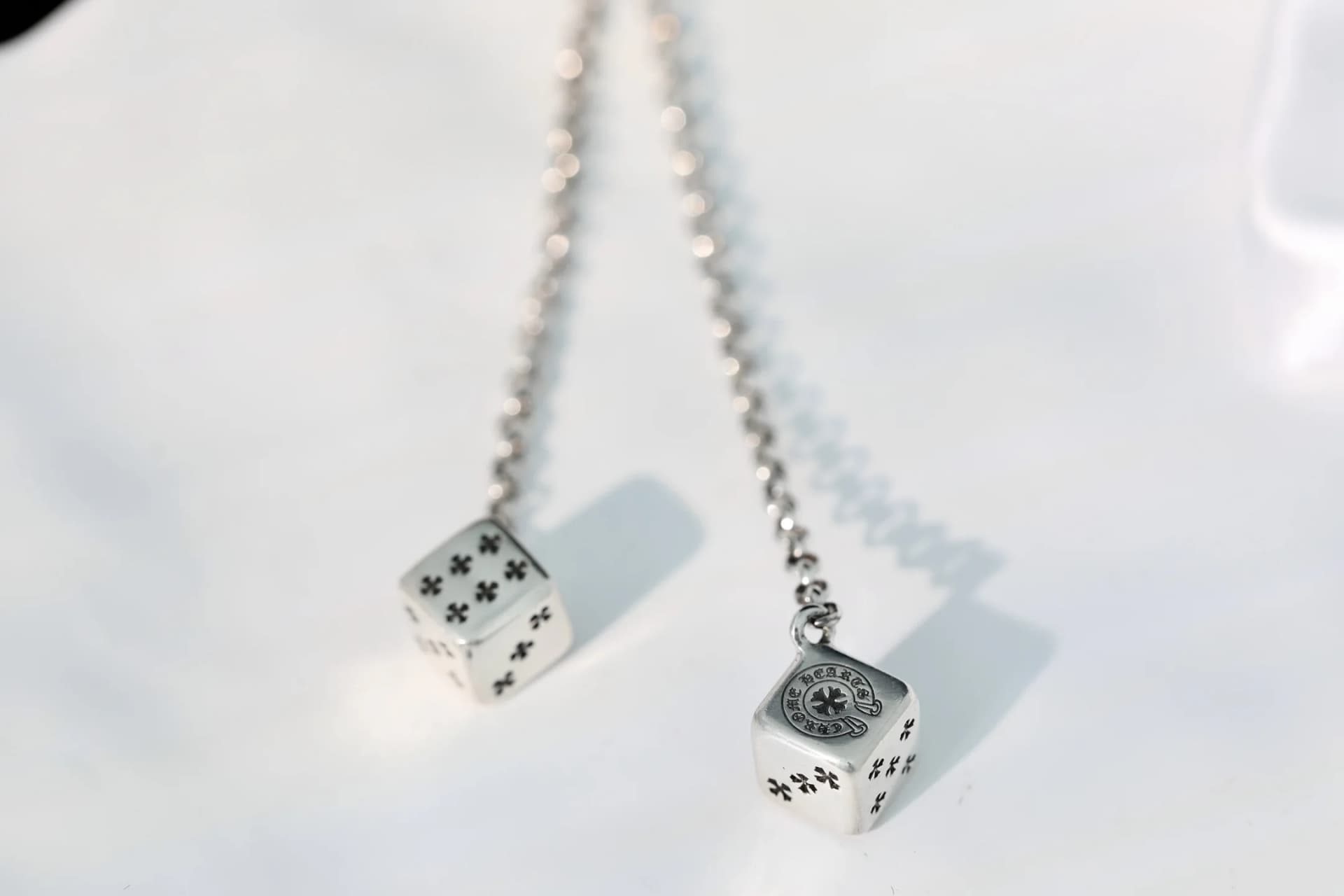 Крупный план подвесок в виде игральных костей с гравировкой крестов Chrome Hearts