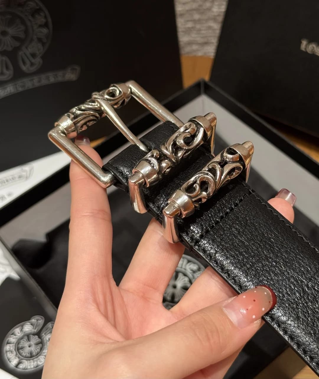 Крупный план серебряной пряжки и фигурных шлёвок ремня Chrome Hearts