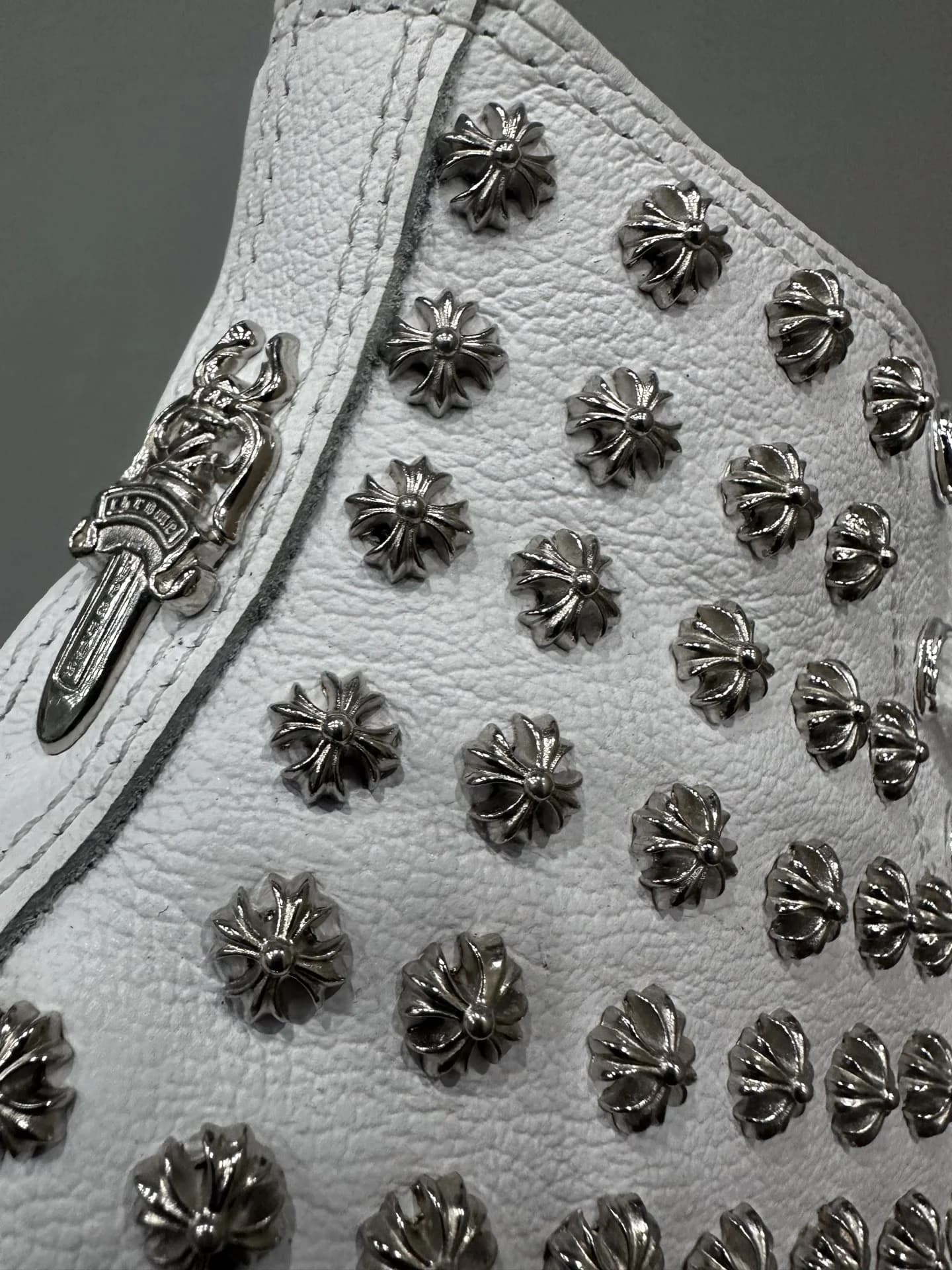 Крупный план заклепок в виде крестов Chrome Hearts на белой коже