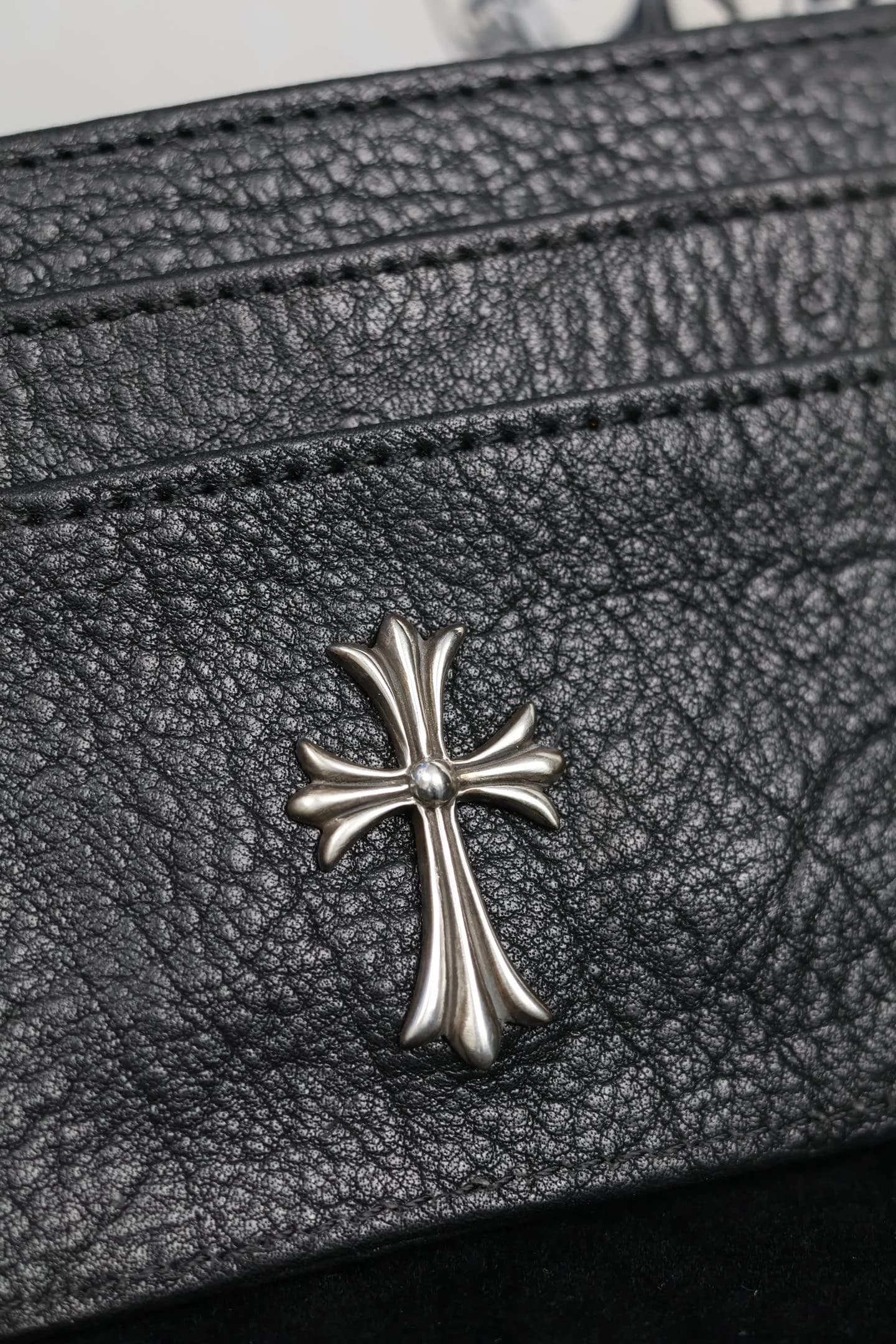 Крупный план серебряной детали CH Cross на фактурной черной коже